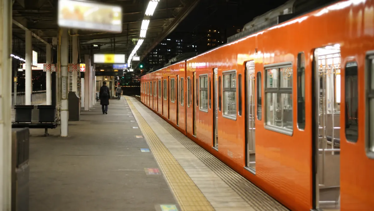 夜のJR駅ホームに停車するオレンジ色の環状線車両