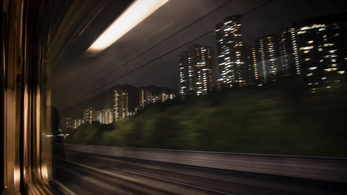 走行中の電車の窓越しに流れる夜のビル群